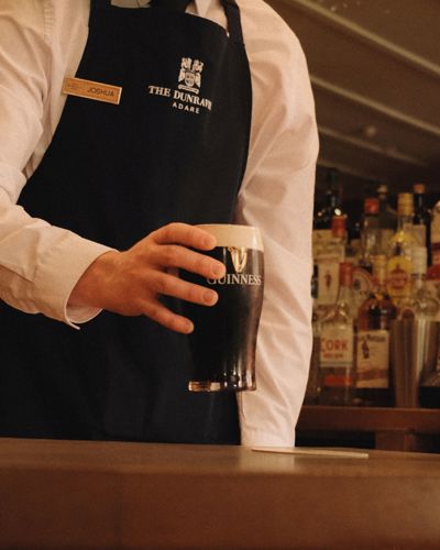 Barman holds a Guiness at the Dunrave Hotel bar in Adare